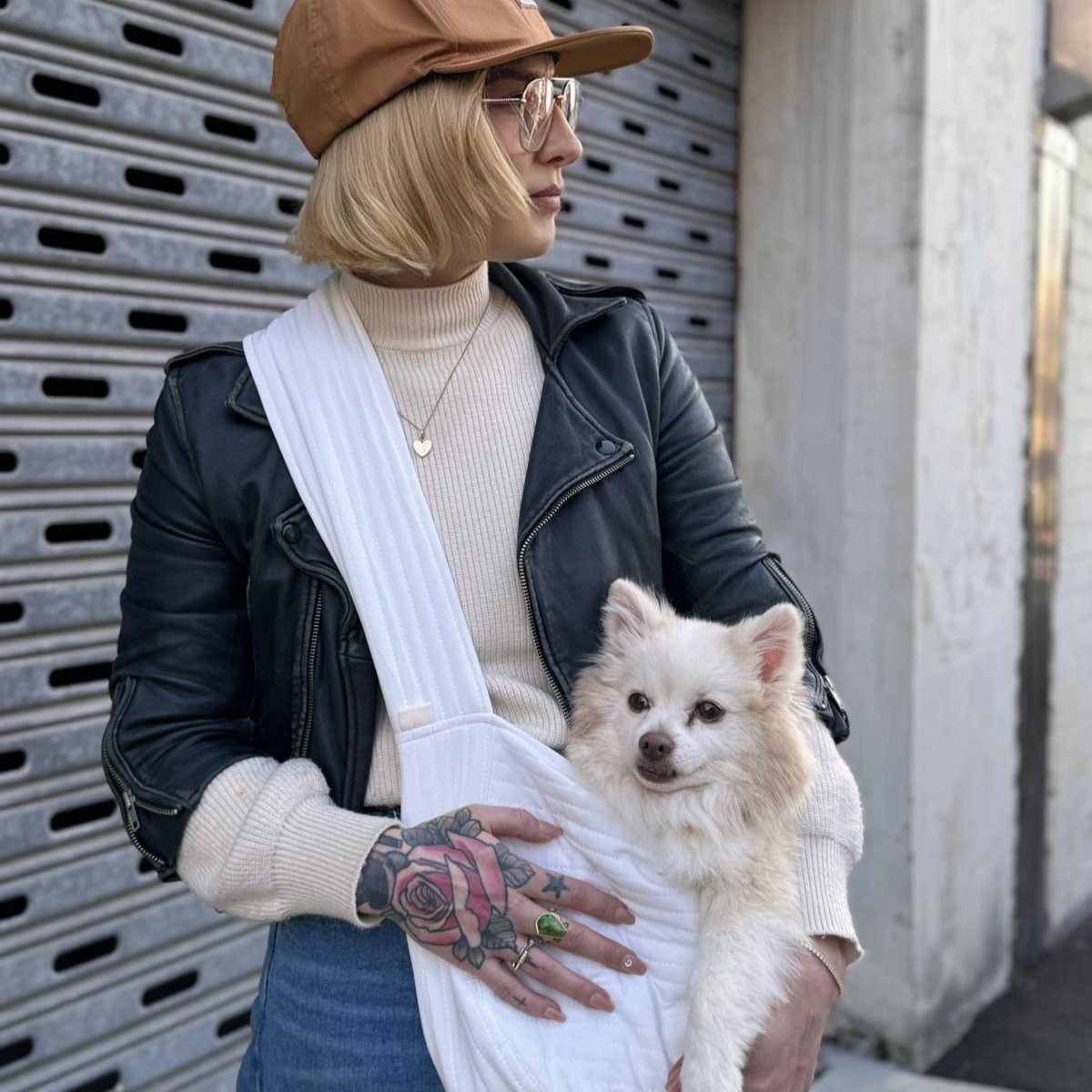 Owner Claire carrying Ozzy, small pomeranian dog in quilted white bag. 